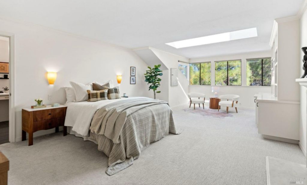 Staged master bedroom featuring a cozy bed, neutral decor, stylish furnishings, and soft lighting, creating a tranquil and inviting atmosphere.
